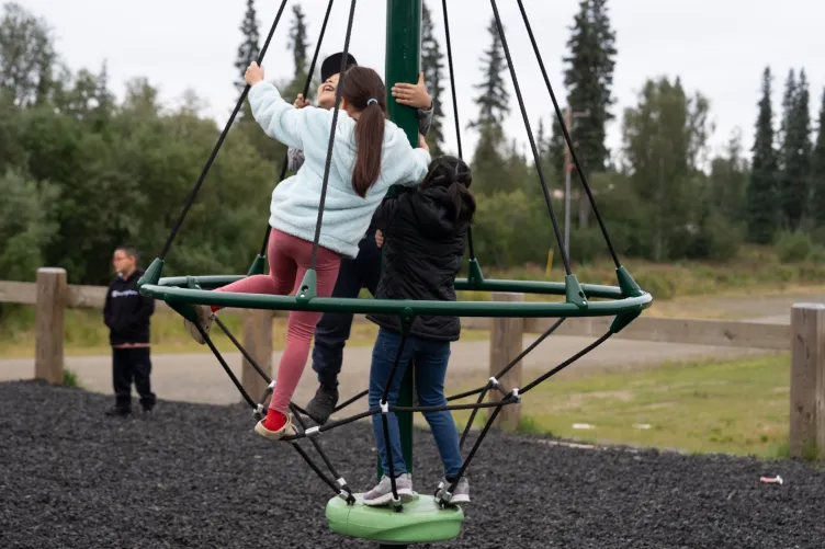 Three kids climb a rope structure.