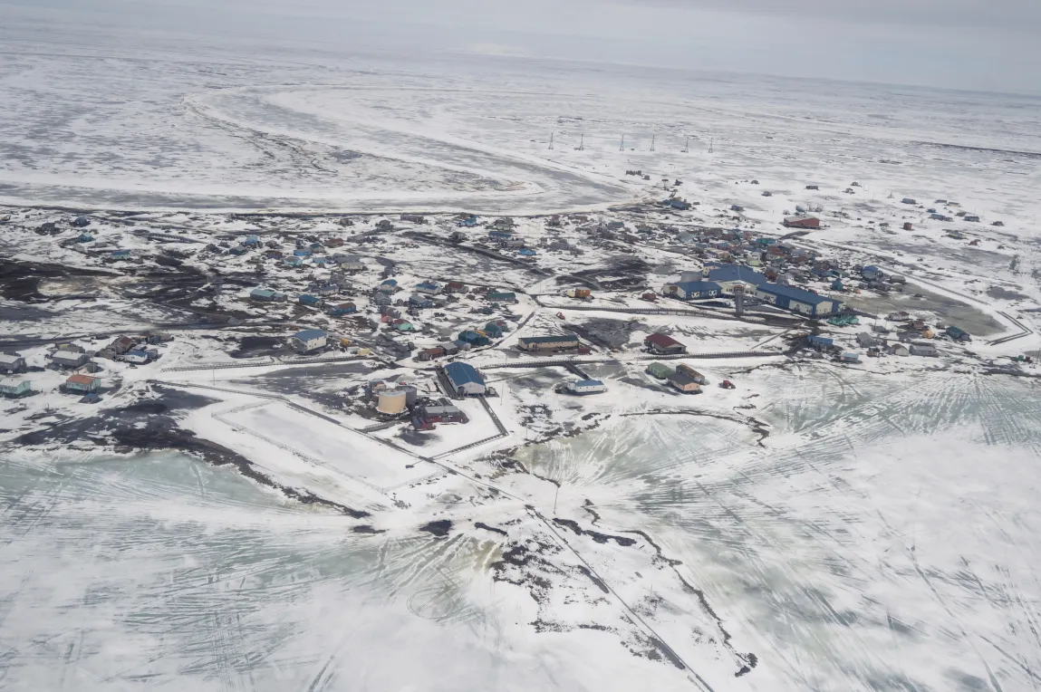 An aerial view of a snow-covered town sitting on the edge of a body of water.