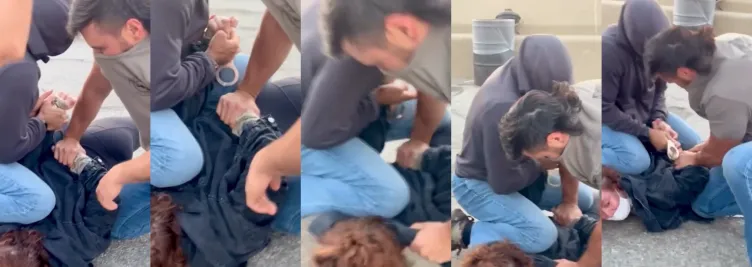 A woman wearing a white mask and blue jacket is pinned to the ground and handcuffed by two men wearing blue jeans and covering their faces with their shirts.