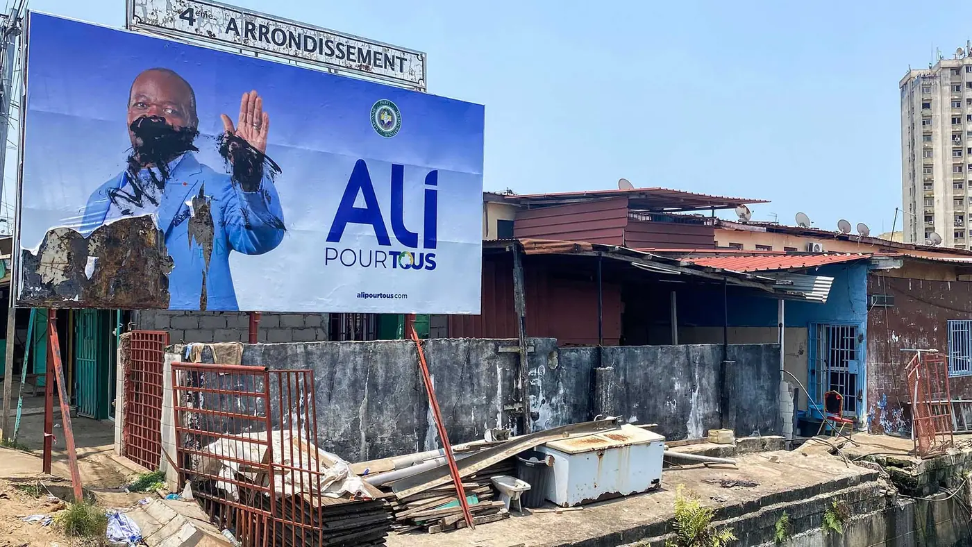 Photo of a billboard showing Ali Bongo's face obscured by graffiti.
