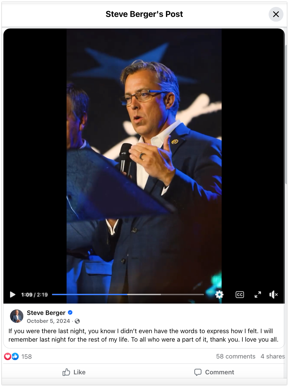 A screen shot of a social media video showing Representative Steve Ogles standing before a lectern and holding a microphone.