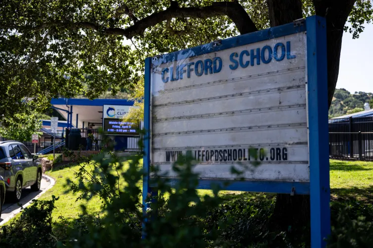 A school building with a sign in front of it that reads, “Clifford School.”