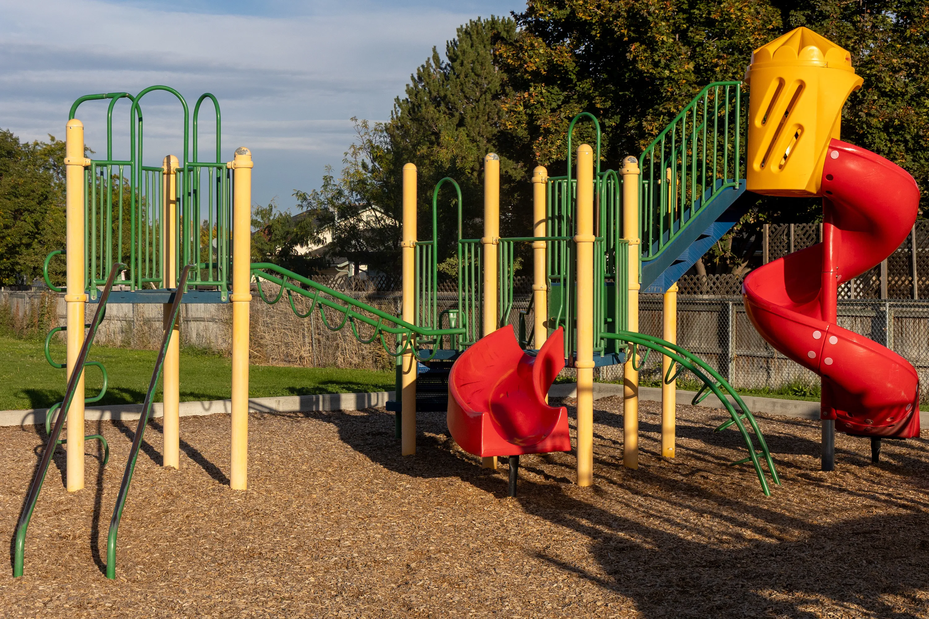 A playground with slides with a wood chip ground surface.